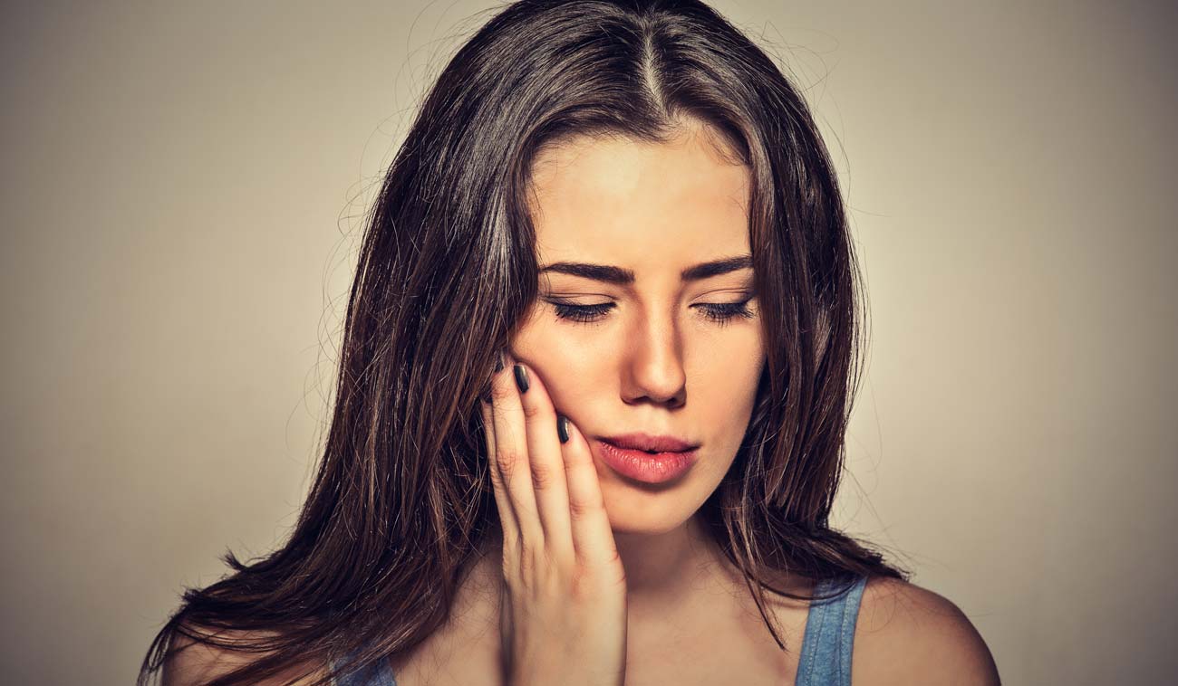Woman holding Her Jaw in Pain from TMJ